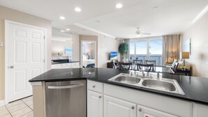 Una cocina moderna con encimera negra, pileta de acero inoxidable y muebles blancos.