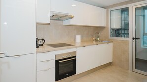 Eine moderne Küche mit weißen Schränken, einem Backofen von Bosch, einer Spüle und einem Fenster mit Jalousien.