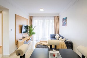 Ein modernes Wohnzimmer mit Flachbildfernseher, einer Couch, einem Esstisch und einem Topfpflanzen.