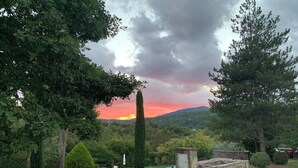 Ländliche Landschaft mit Sonnenuntergang, einer Holzbank und einer Steinstruktur.