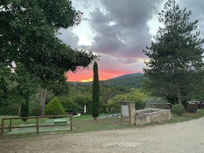 Ländliche Landschaft mit Sonnenuntergang, einer Holzbank und einer Steinstruktur.