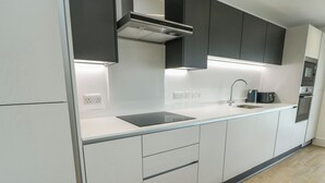 Una cocina moderna con armarios blancos, encimera negra y horno integrado.