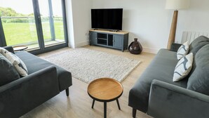 Una sala moderna con televisor, sofá y una pequeña mesa de madera.