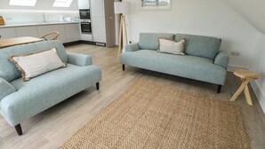 A modern living room with a sofa, armchair, and a small side table. - Glynllifon 7 (Marianglas)