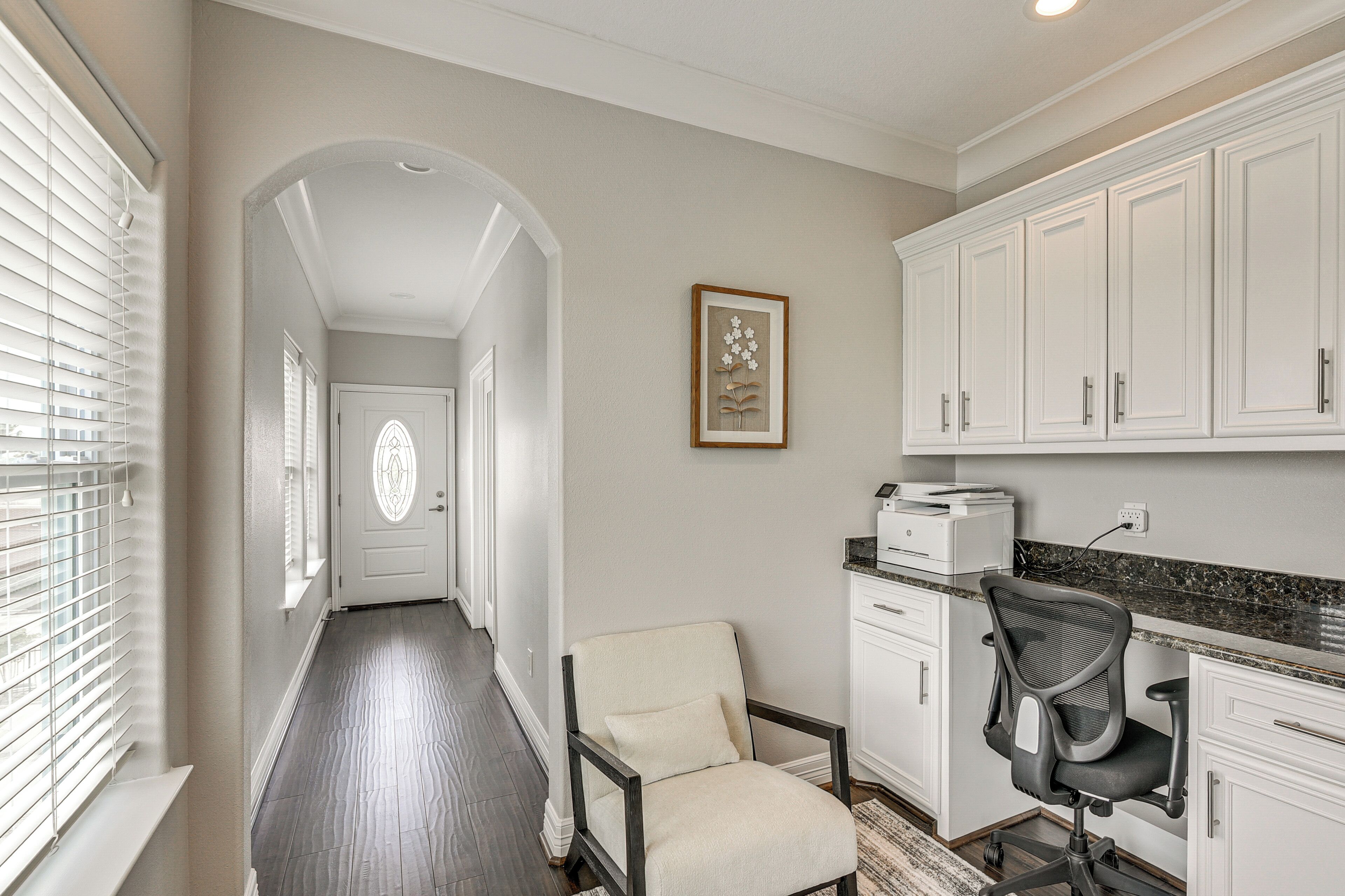 A hallway with a door, a chair, a desk, and cabinets.