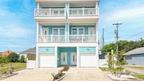 Ein zweistöckiges Gebäude mit Balkon, Garage und kleinem Garten.