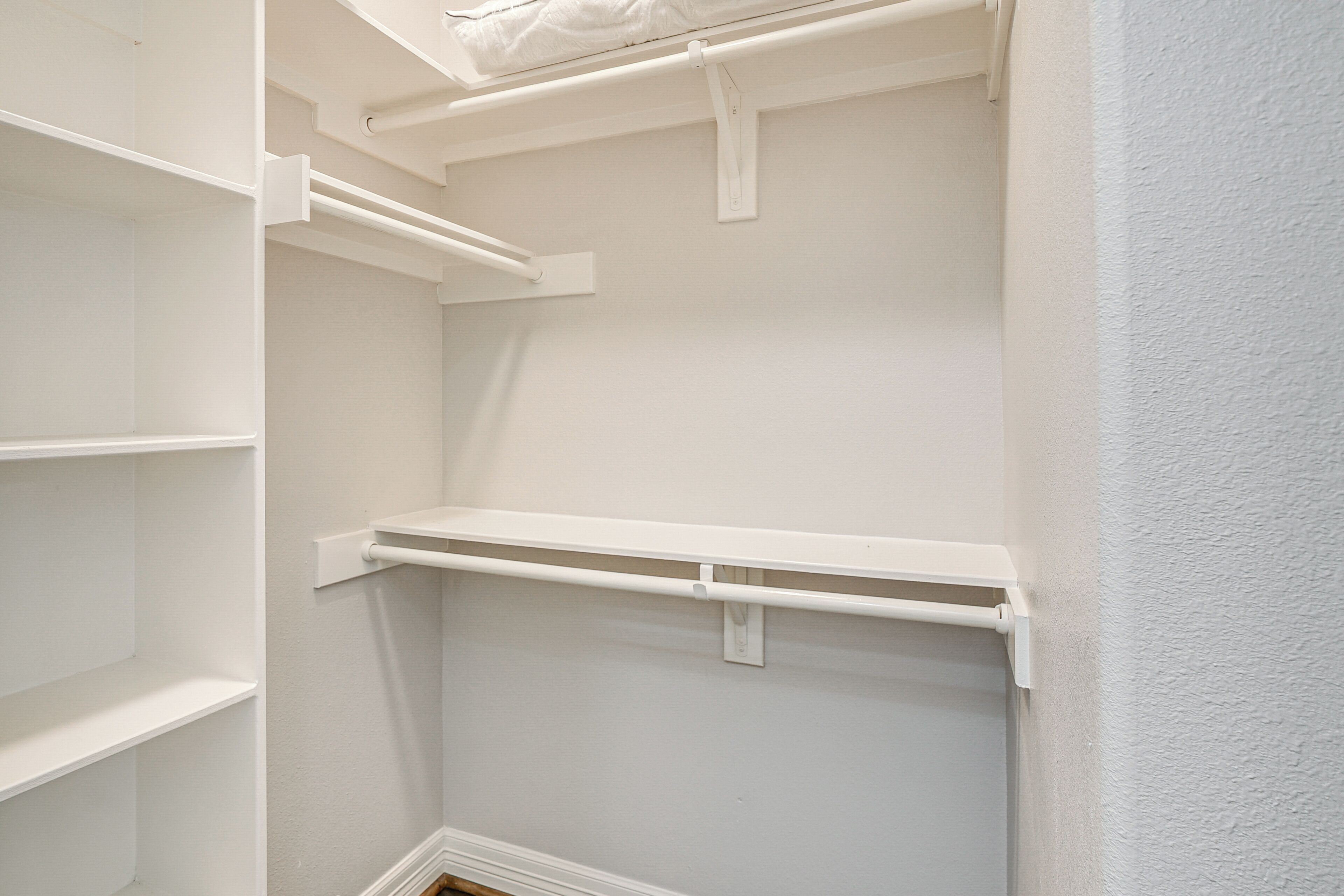 A white closet with multiple shelves and a hanging rod.