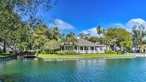 A house with a covered porch, a pond, and surrounding greenery. - Pool Access! St Simons Island Getaway w/ Balcony (St. Simons Island)