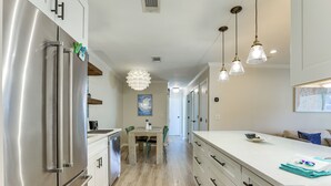 A modern kitchen with stainless steel appliances, a dining area with a table and chairs, and pendant lighting. - Pool Access! St Simons Island Getaway w/ Balcony (St. Simons Island)
