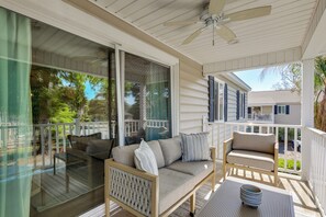 Eine überdachte Veranda mit einer Couch, einem Sessel und einem Tisch mit Geschirr.