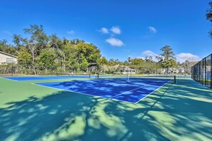 A tennis court with a net, surrounded by trees and a fence. - Pool Access! St Simons Island Getaway w/ Balcony (St. Simons Island)