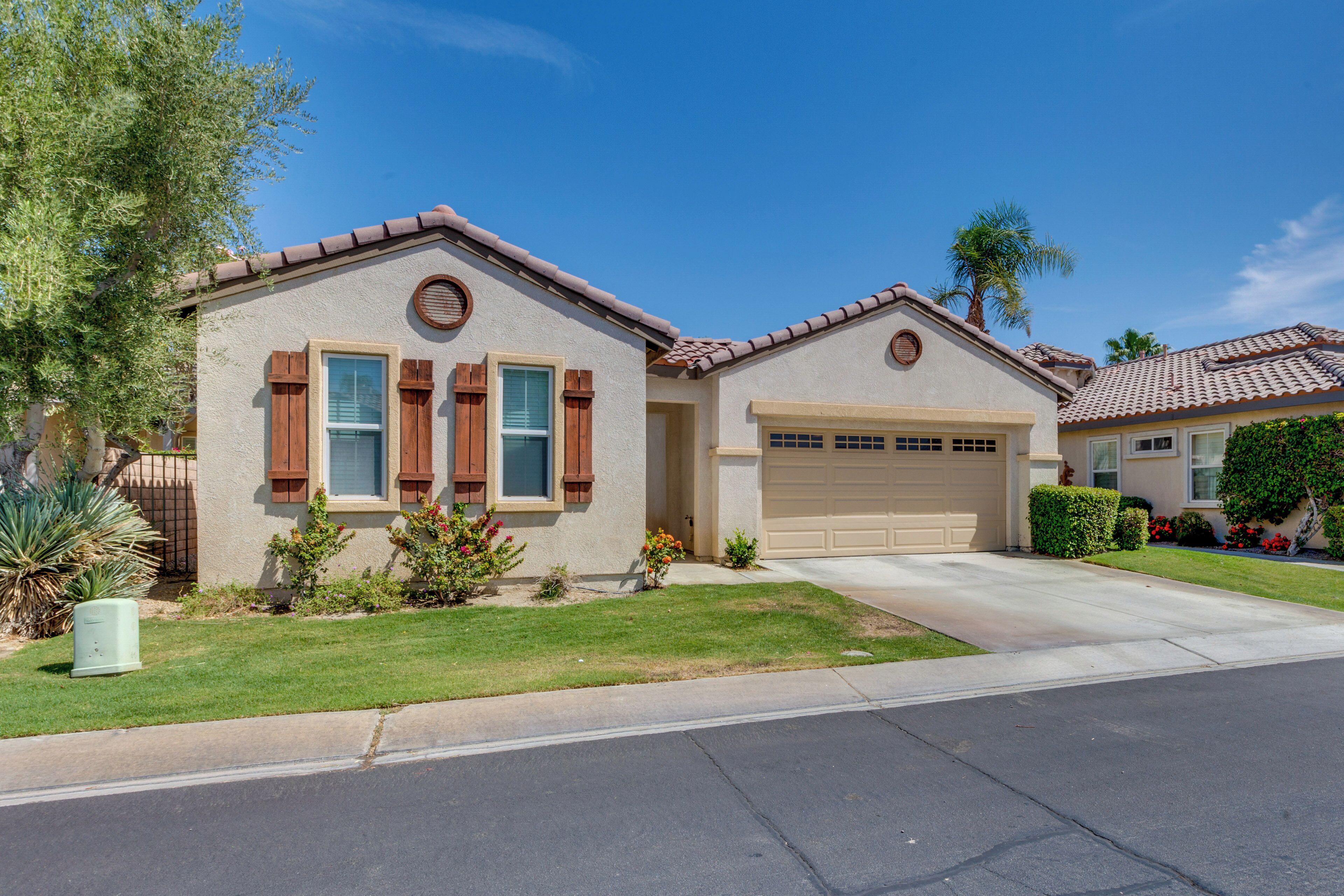 A residential house with a garage, a well-maintained lawn, and a clear sky.