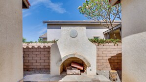 A stone-built outdoor fireplace with a brick wall and a clear blue sky in the background. - Pool Access + Mtn Views! Extended Escape in Indio (Indio)
