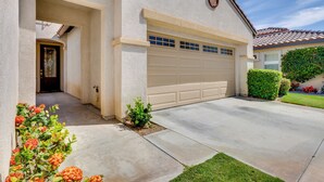 A residential house with a garage, a front door, and a small garden with flowers. - Pool Access + Mtn Views! Extended Escape in Indio (Indio)
