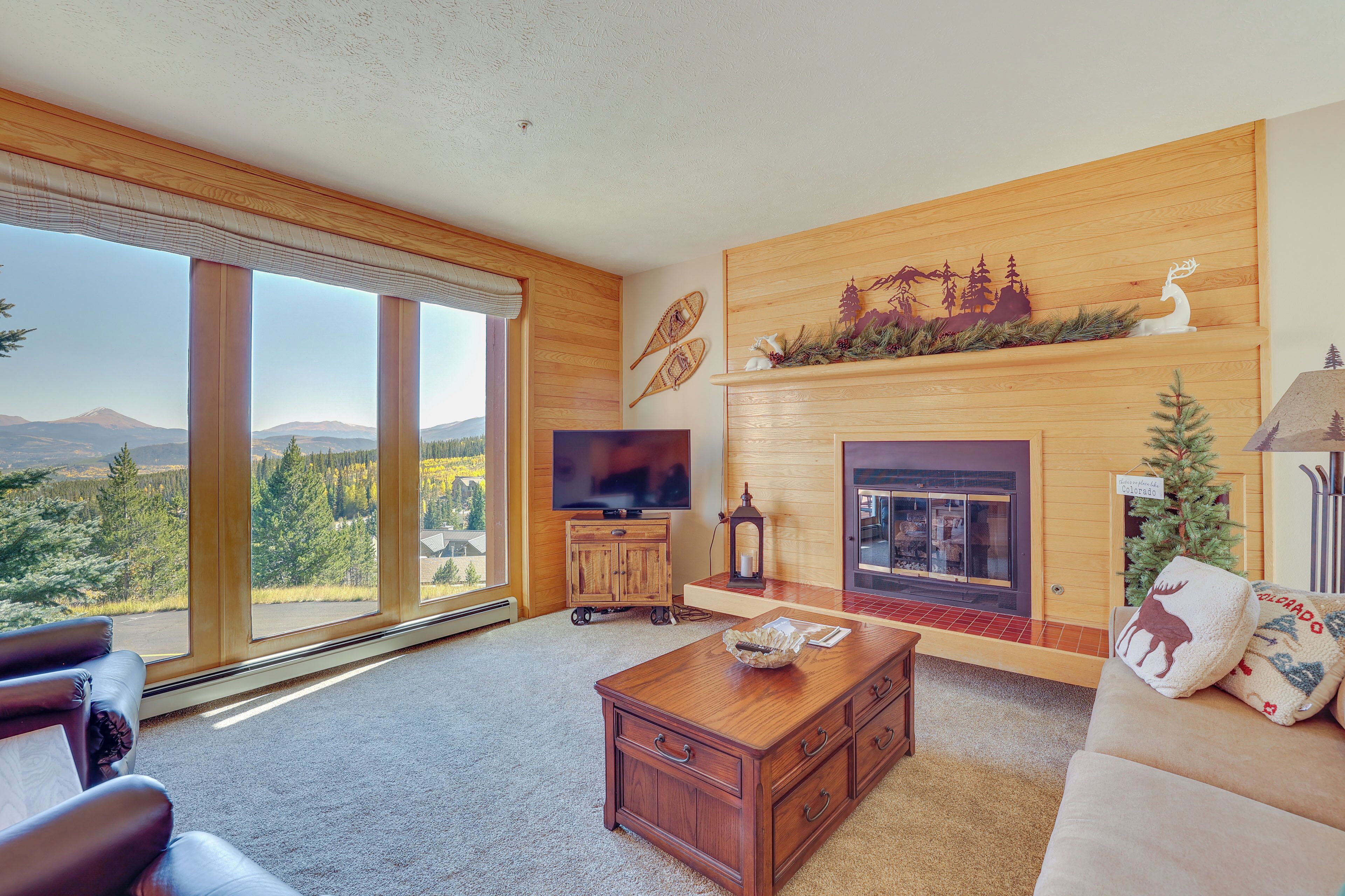 A spacious living room with a large window, a fireplace, and a television.