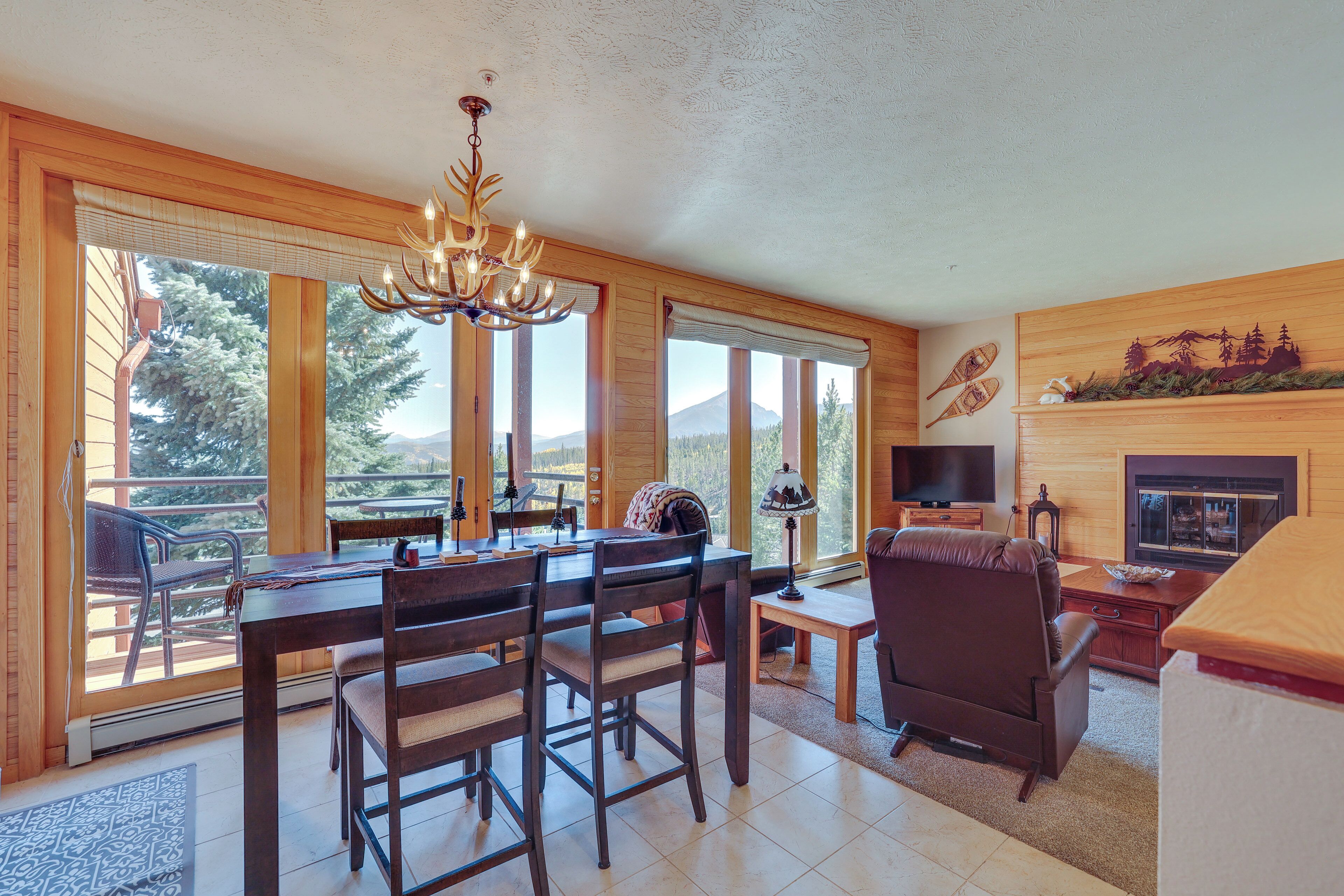 A cozy living room with a wooden dining table, chairs, a fireplace, and a television.