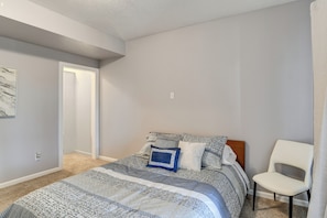 A bedroom with a bed, a chair, and a door. - 4 Mi to Easter Lake Park! Inviting Rental w/ Patio (Des Moines)