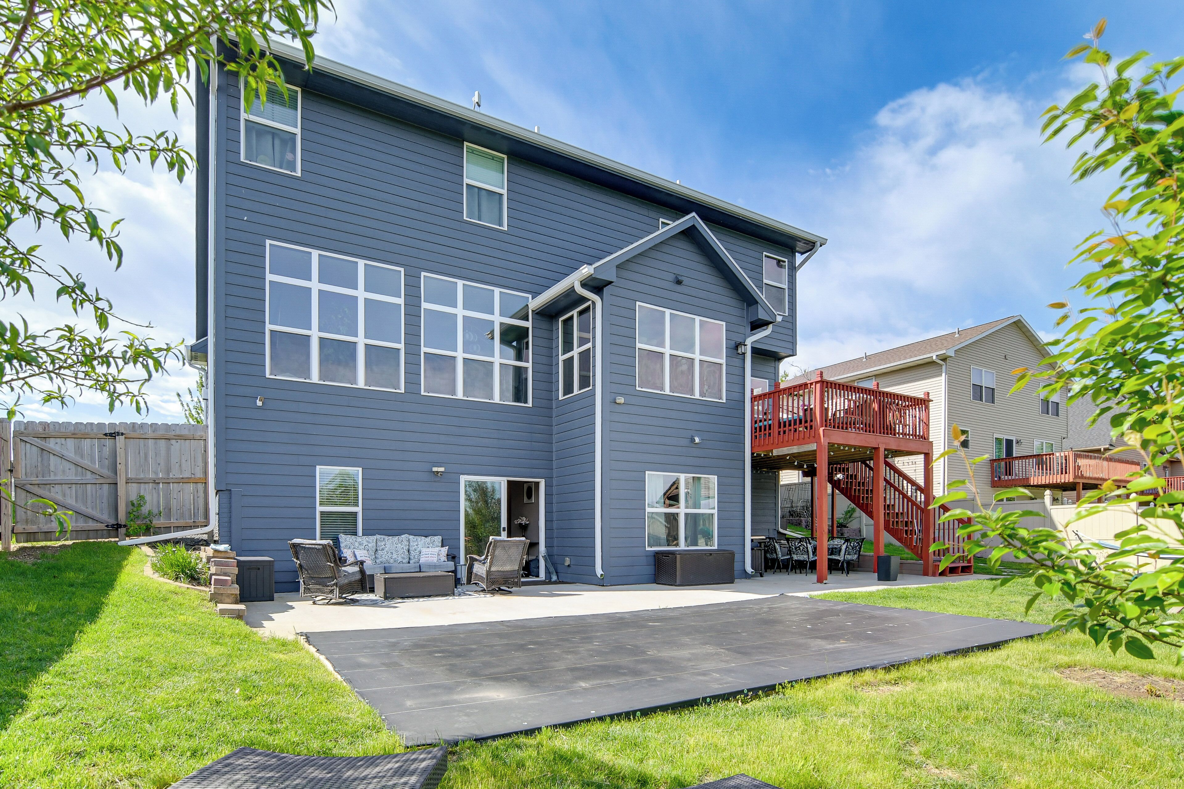 A two-story residential building with a patio, outdoor seating, and a red staircase.
