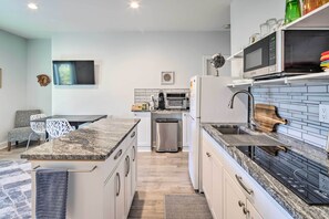 Eine moderne Küche mit Granit-Arbeitsplatten, einem eingebauten Backofen, einer Mikrowelle und einem Edelstahl-Kühlschrank.