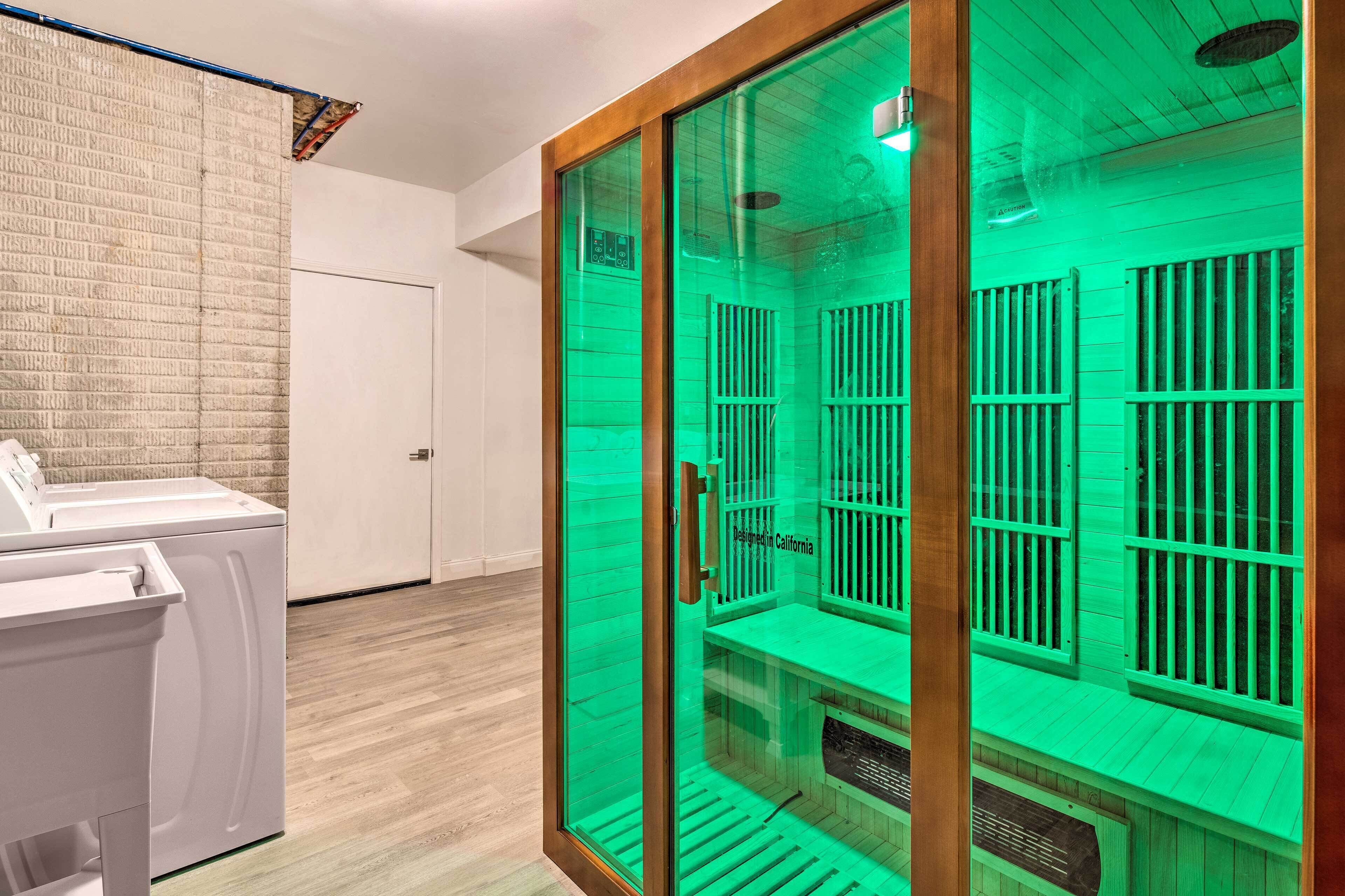 A sauna room with a glass door, a wooden bench, and a control panel.