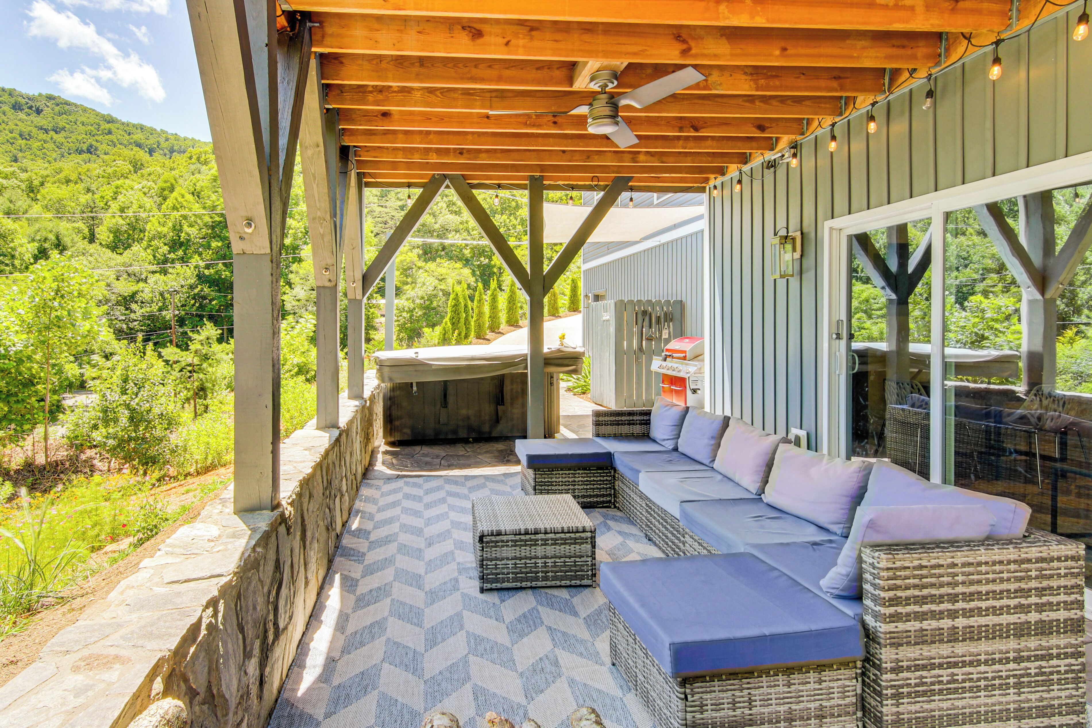 An outdoor patio with wicker furniture and a view of a lush green landscape.
