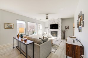 Ein modernes Wohnzimmer mit Kamin, einer Couch, einem Couchtisch und einem an der Wand befestigten Fernseher.