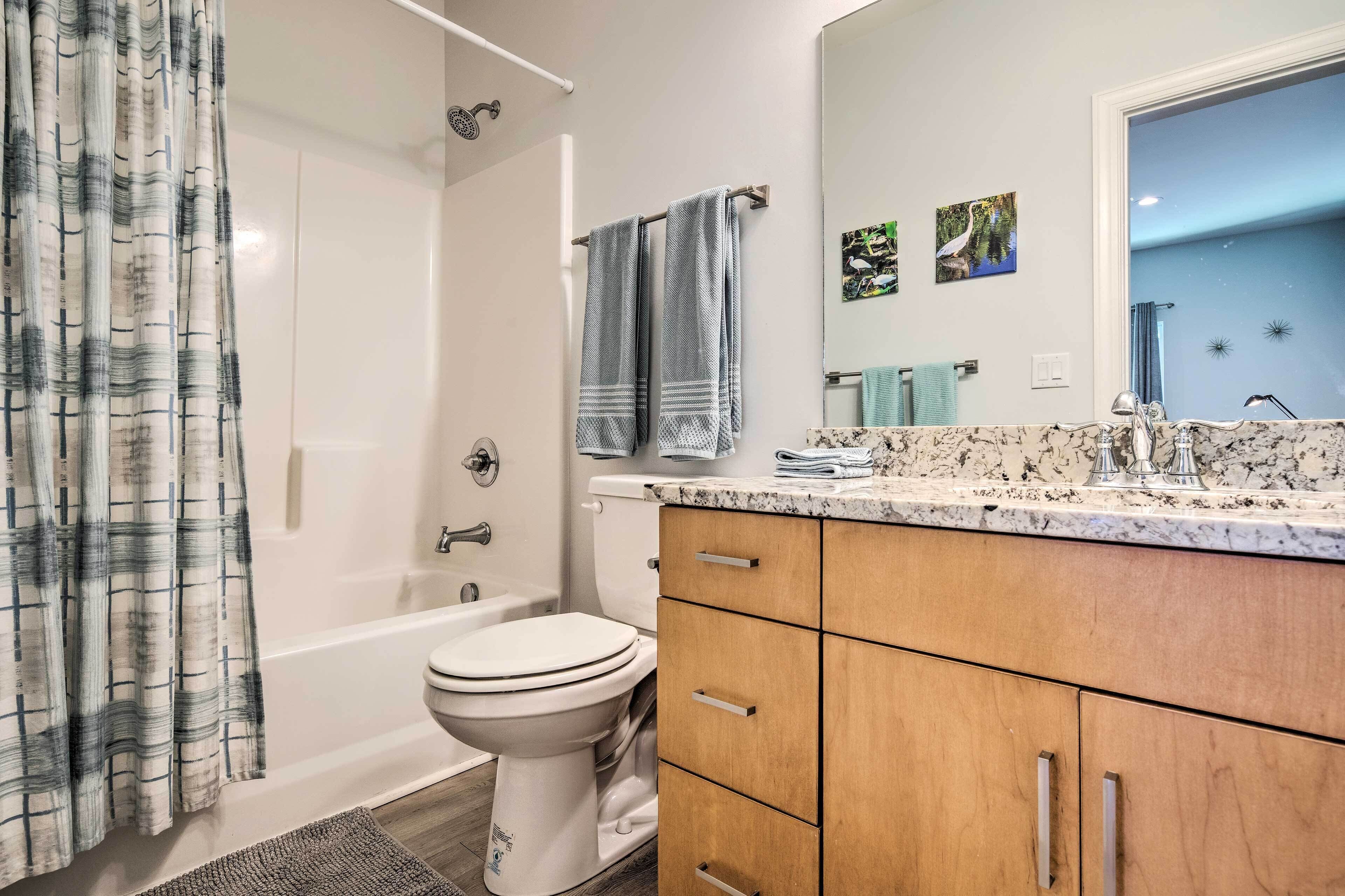 A bathroom with a bathtub, toilet, and vanity with a mirror.