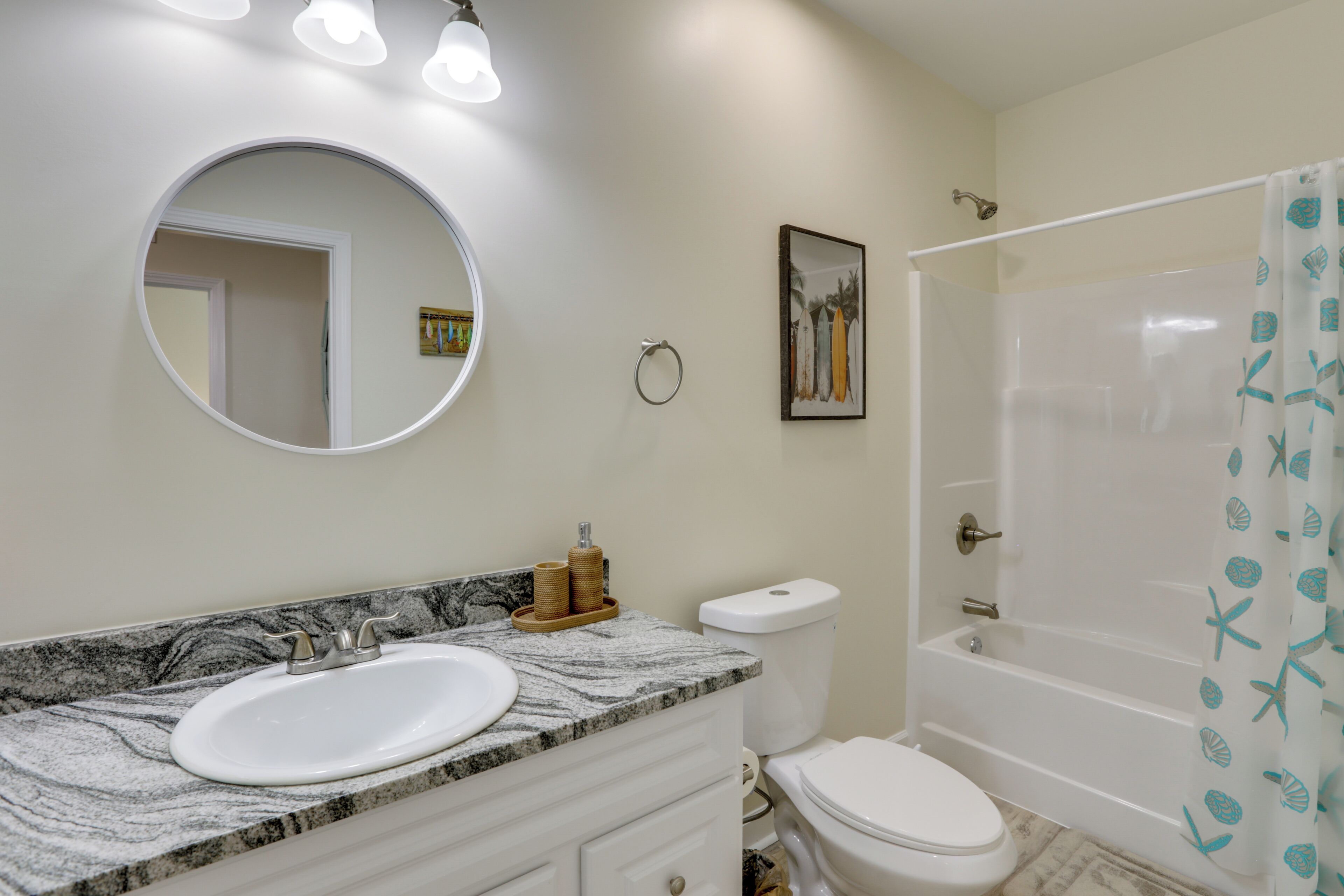 A bathroom with a round mirror, a sink, a toilet, and a bathtub.