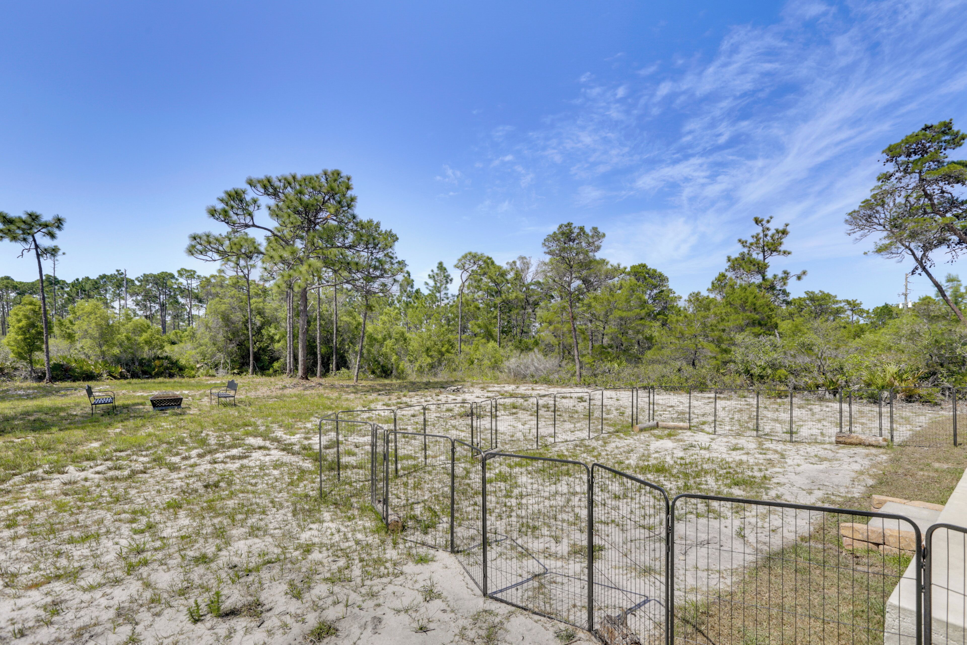 A fenced outdoor area with benches, trees, and a clear sky.