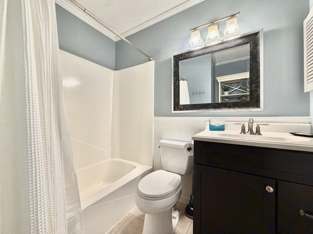 Une salle de bain équipée d’une baignoire, de toilettes, d’un meuble-lavabo et d’un miroir.