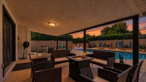 An outdoor patio with wicker furniture, a fire pit, and a view of a swimming pool. - Sunrise-Sparkling Pool-BBQ Grill-Mins to Old Town (Scottsdale)