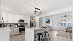 A modern kitchen with white cabinetry, stainless steel appliances, and a central island with stools. - Sunrise-Sparkling Pool-BBQ Grill-Mins to Old Town (Scottsdale)