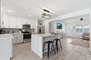 A modern kitchen with white cabinetry, stainless steel appliances, and a central island with stools.
