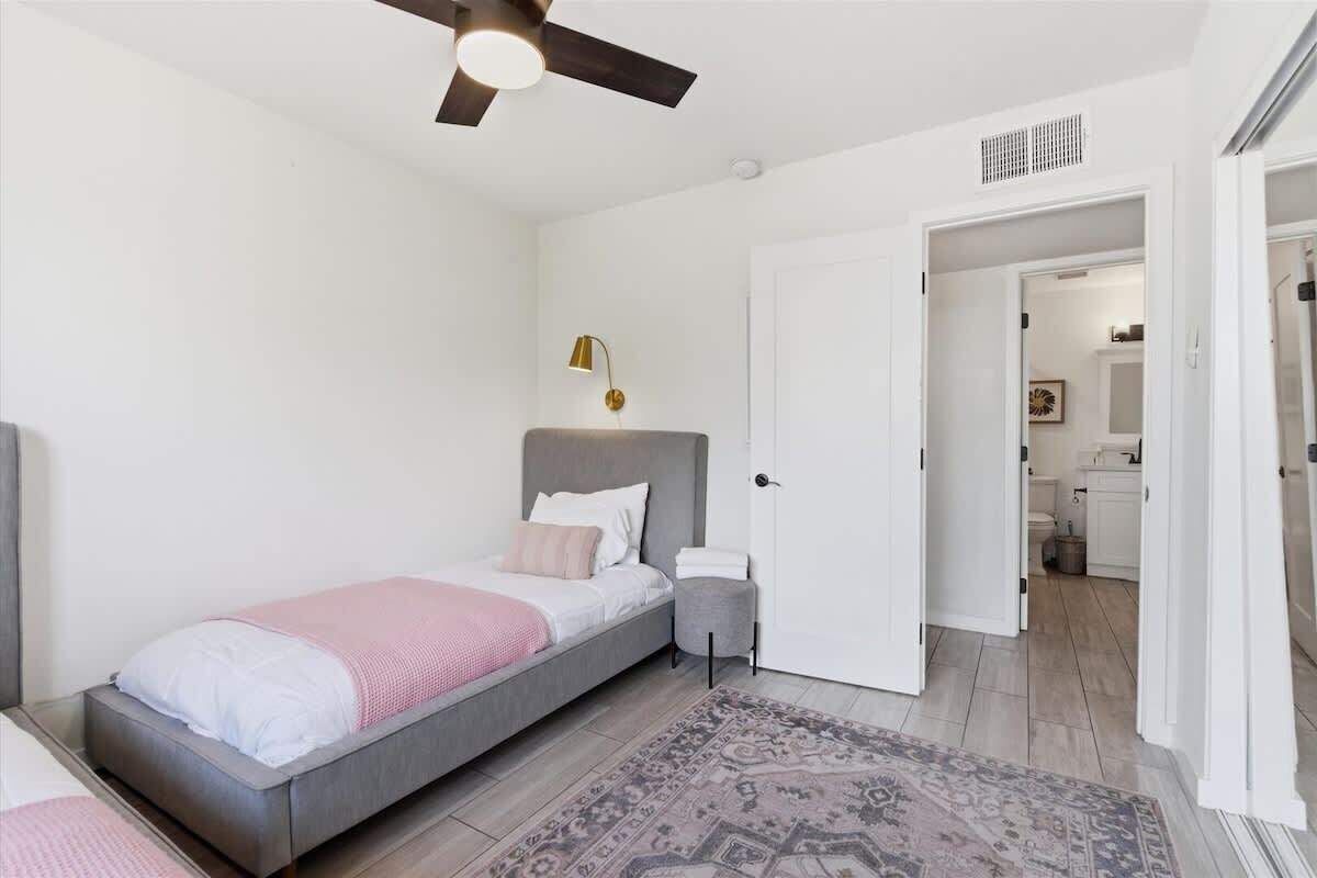 Une chambre à coucher avec un lit, une table de chevet et un ventilateur de plafond.