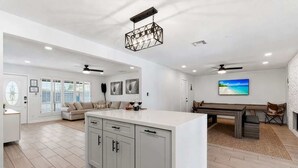 A spacious living area with a large island, a dining table, and a view of the outdoors. - Sunrise-Sparkling Pool-BBQ Grill-Mins to Old Town (Scottsdale)
