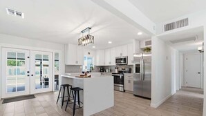 A modern kitchen with white cabinetry, a central island, and stainless steel appliances. - Sunrise-Sparkling Pool-BBQ Grill-Mins to Old Town (Scottsdale)