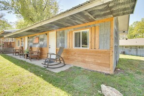 Eine Holzhütte mit Veranda, Schaukelstühlen und einem kleinen Tisch mit Stühlen.
