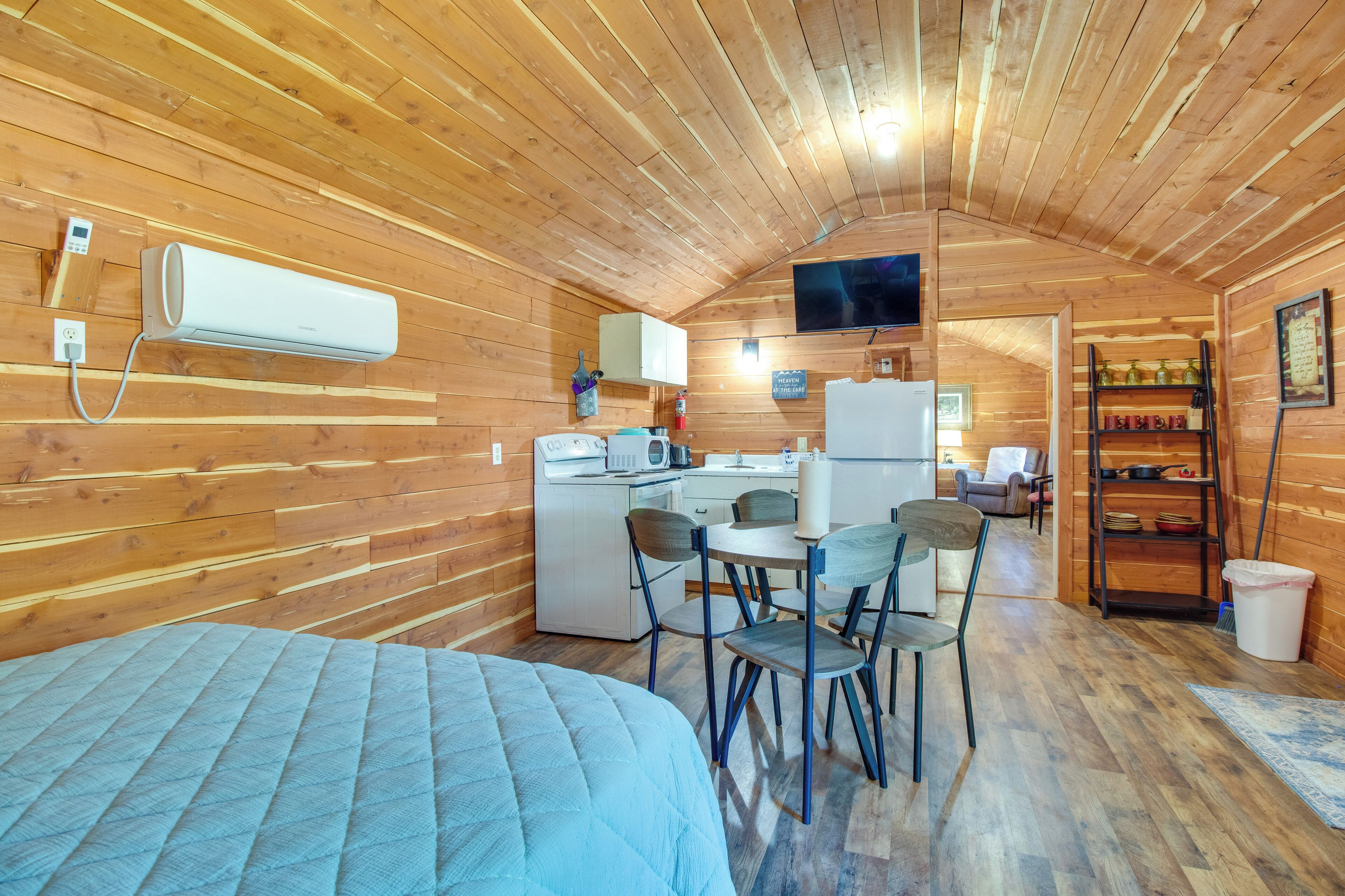 Een gezellig chalet met kitchenette, eethoek en bed.