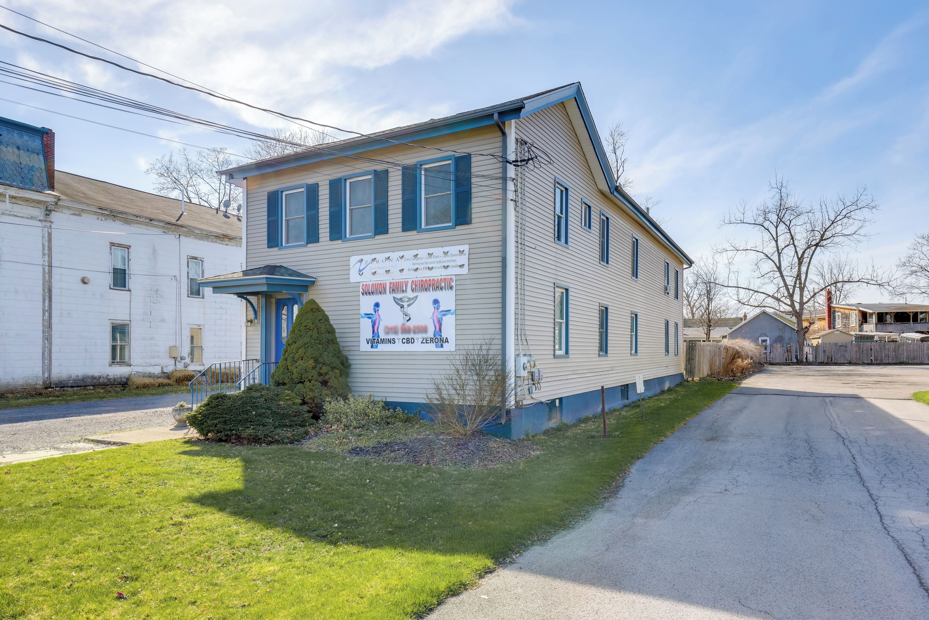 A two-story building with a sign advertising Solonon Family Chiropractic, featuring Vitamins, CBD, and Zeroa.