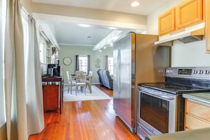 A kitchen with a stainless steel refrigerator, oven, and stove. There is a dining area with a table and chairs.