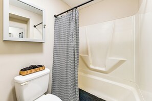 A bathroom with a toilet, a shower curtain, a bathtub, and a mirror. - Walkable 2-unit Home Near Dtwn Seneca Falls! (Seneca Falls)