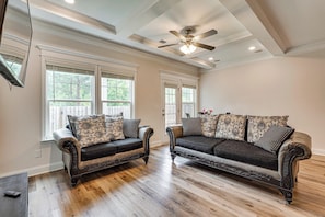 A living room with two dark leather sofas, patterned cushions, a ceiling fan, and large windows. - Easy Access to Golf Club & Dtwn: Augusta Basecamp (Evans)