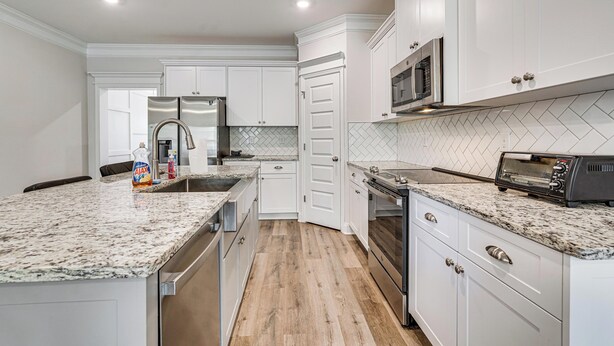 A modern kitchen with white cabinetry, granite countertops, stainless steel appliances, and a herringbone tile backsplash. - Easy Access to Golf Club & Dtwn: Augusta Basecamp (Evans)