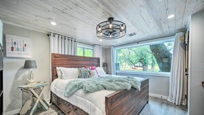 Ein Schlafzimmer mit einem hölzernen Bett, einem Nachttisch, einer Lampe und einem Fenster mit Vorhängen.