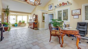A spacious living room with a high ceiling, a chandelier, and a dining area with a table and chairs. - Emigrant Lodge w/ Spa: 3 Suites Near Yellowstone (Emigrant)