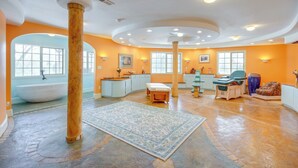 A spacious bathroom with a large bathtub, a wooden column, and a patterned rug. - Emigrant Lodge w/ Spa: 3 Suites Near Yellowstone (Emigrant)