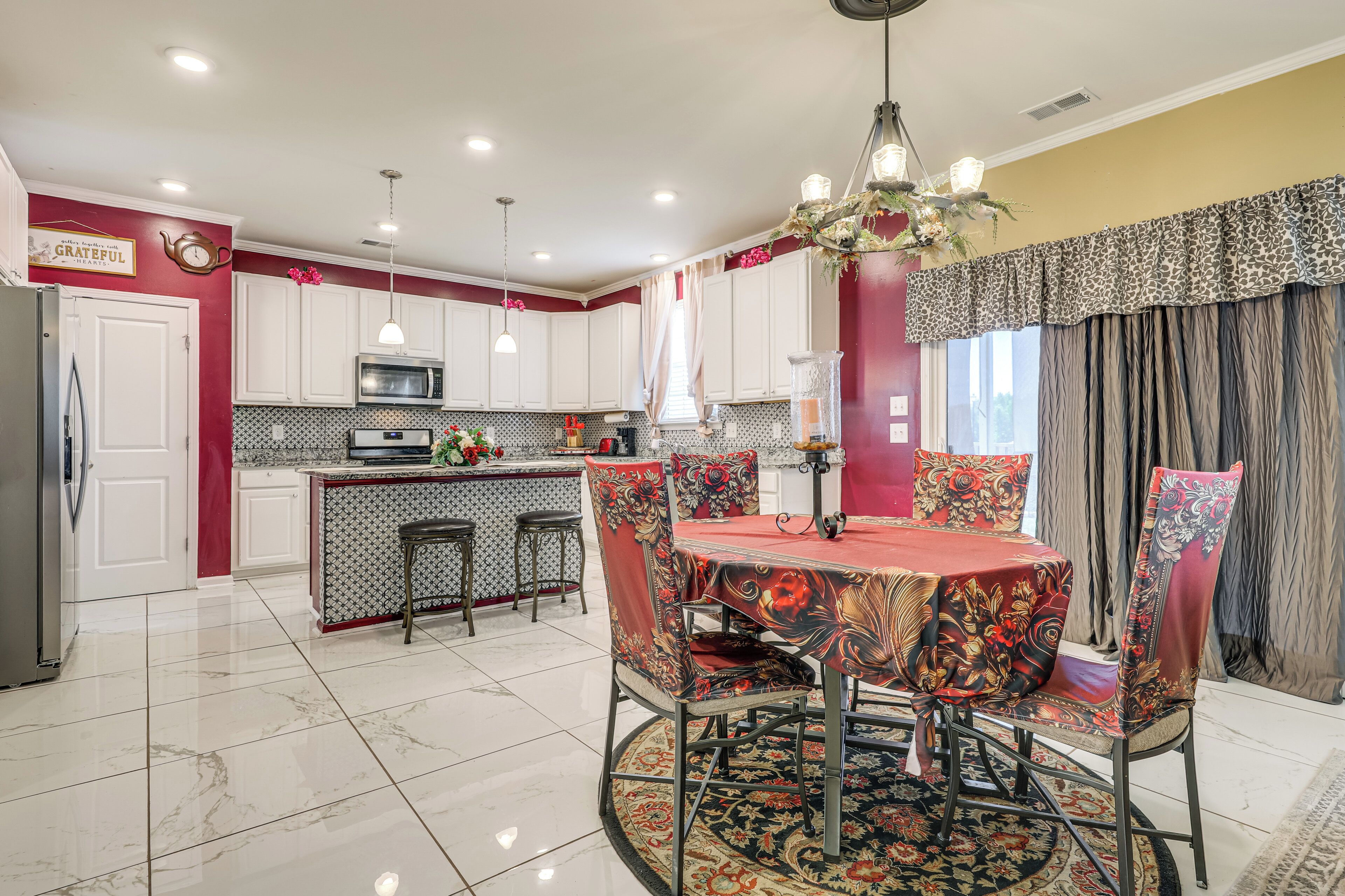 A modern kitchen with white cabinets, a central island, and a dining area with a round table and chairs.