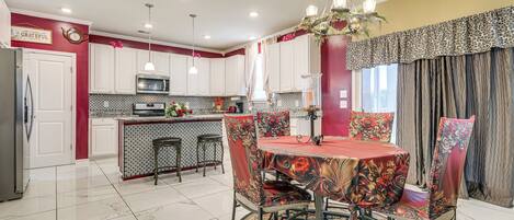 A modern kitchen with white cabinets, a central island, and a dining area with a round table and chairs.