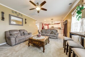 A living room with a ceiling fan, two sofas, a coffee table, and a dining area with a table and chairs. - Lakes, Gardens & More! Getaway in Moncks Corner (Moncks Corner)