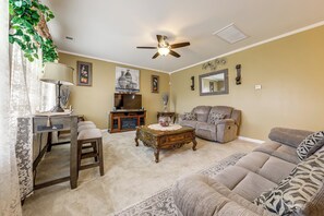 A living room with a ceiling fan, a sofa, a coffee table, a TV stand, and a lamp. - Lakes, Gardens & More! Getaway in Moncks Corner (Moncks Corner)